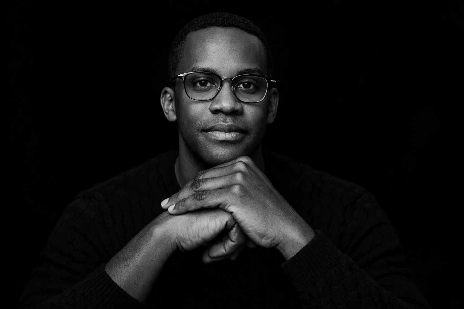 Antonio M. Haynes — formal portrait with clasped hands, direct eye contact, conveying authority and approachability